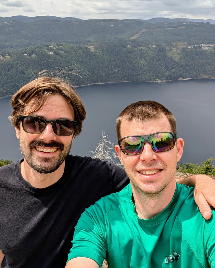Casey and his brother Alex smiling on a mountaintop above a lake